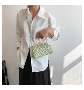Detail of light green woven handbag featuring heart-shaped gold clasp and chain
