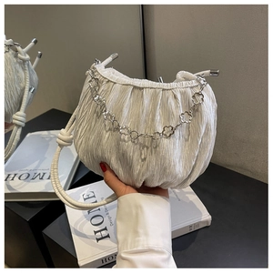 Detail of white pleated cloud bag with elegant silver floral chain and fine texture