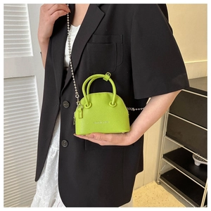 Close-up of lime green shell bag with silver ball chain and fashion text detail