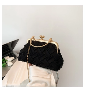 Detail of black woven evening clutch bag with golden metal frame and chain strap