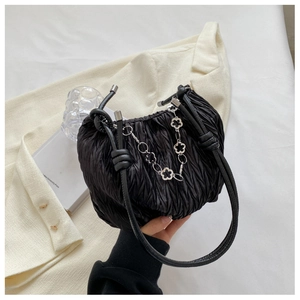 Detail of black pleated cloud bag featuring delicate silver metal flower chain and soft texture