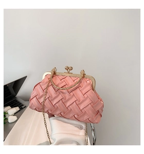 Detail of pink woven handbag with golden metal handle and elegant pearl clasp closure