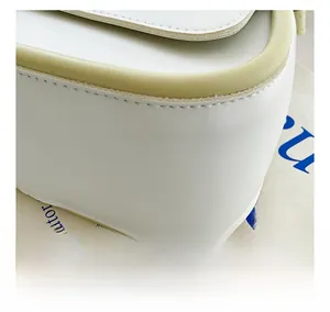 Close-up of white leather saddle bag showing precise stitching and light green trim details