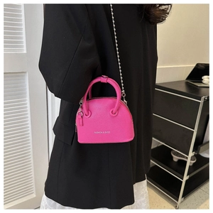 Magenta shell-shaped crossbody bag with chain strap shown on model's side back view