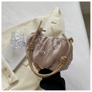 Detail of pleated champagne tote bag with decorative metal chain and flower charm