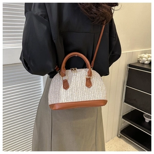 Detail der gewebten Muscheltasche mit braunem Lederbesatz und verstellbarem Riemen am Model