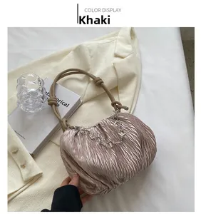 Detail of khaki pleated cloud bag featuring a knotted handle and floral metal chain