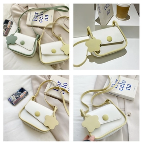 Close-up of minimalist cream crossbody bag with mint green piping and floral charm detail