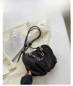 Detailed view of black pleated canvas bag with elegant silver floral chain strap