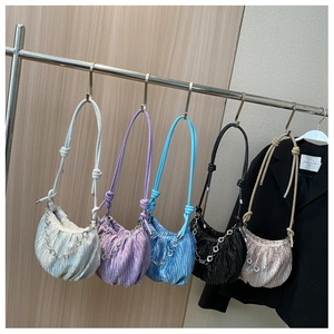 Row of pleated ruched cloud bags in various colors on display with floral metal chains