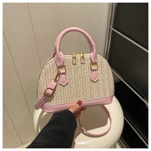 Detail der gewebten Strohhandtasche mit rosa Lederbesatz und Schultergurt