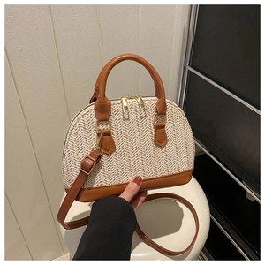 Detailansicht der handgewebten Stroh-Muscheltasche mit Lederbesatz und Goldreißverschlüssen