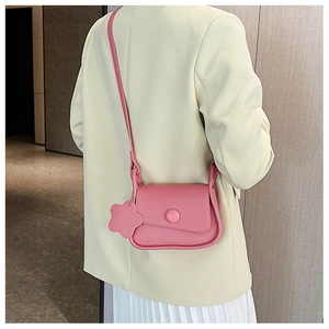 Pink matte leather crossbody bag back view with decorative flower charm accessory