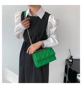 Detail of green quilted crossbody bag with gold chain strap on a fashion model