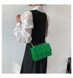 Detail of green quilted crossbody bag with geometric pattern and gold chain strap