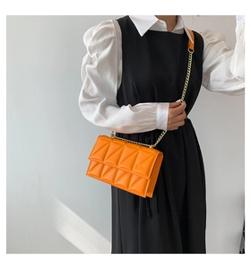 Close-up of bright orange quilted chain bag on a model showing size and texture