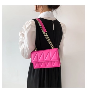 Detail of fuchsia quilted handbag with gold chain strap worn by a model in black and white