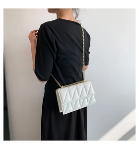 Close-up of white geometric quilted crossbody bag with elegant gold chain strap