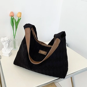 Black quilted diamond pattern canvas tote bag with brown leather shoulder straps