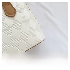 Detailed close-up of white quilted PU leather texture and brown stitched handle on shell bag