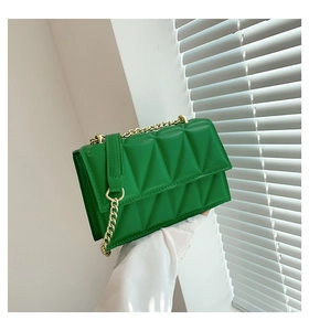 Detail of green quilted faux leather crossbody bag with elegant gold metal chain strap