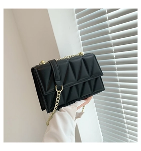 Close-up of black quilted shoulder bag featuring gold chain strap and sleek texture
