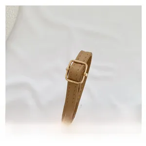 Close-up of adjustable brown leather shoulder strap with gold-tone buckle and neat stitching