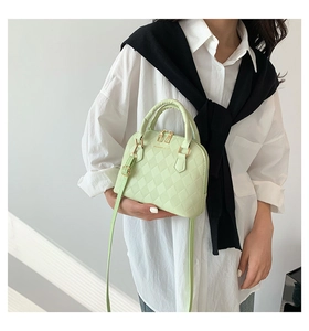 Detail of mint green quilted shell bag showing texture and adjustable strap on model