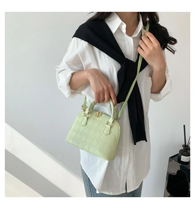 Close-up of mint green shell bag featuring quilted texture and golden hardware accents