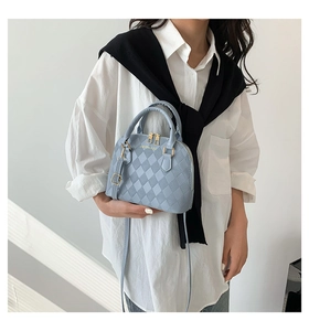 Detail of light blue shell bag with 3D rhombus texture and golden zipper