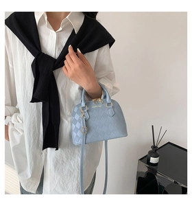 Detail of light blue crossbody bag with quilted diamond pattern and gold hardware
