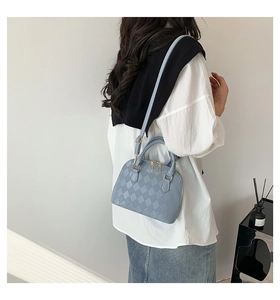 Detailed view of light blue shell bag with quilted texture and gold zipper hardware