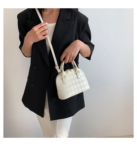 Detail of white quilted shell bag with gold hardware and elegant textured finish