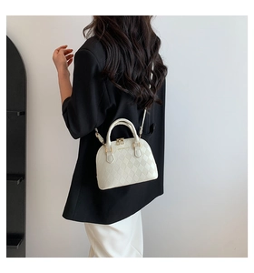 White shell-shaped quilted shoulder bag with gold hardware shown on a model