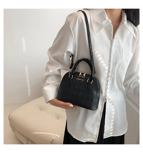 Detail of black woven shell bag with gold zippers and textured grid pattern