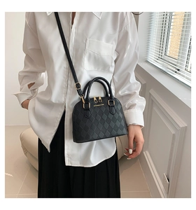 Detail of a black quilted shell bag with gold zippers and an adjustable shoulder strap