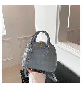 Close-up of light blue shell-shaped handbag showing quilted texture and gold hardware
