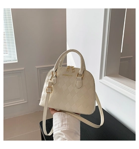 Detail view of white shell bag with quilted texture and gold hardware accessories