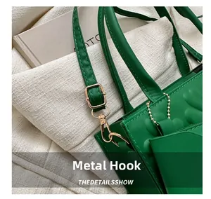Detail of green leather handbag showing golden metal hook and precise stitching quality
