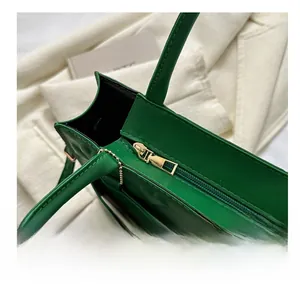Detail of smooth gold zipper and dark green quilted leather texture on square handbag