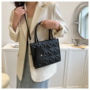 Detail of black crossbody bag with clover embossing and small clip-on coin purse