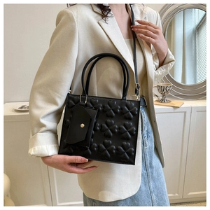 Detail of black clover-embossed tote bag with matching coin purse and adjustable strap