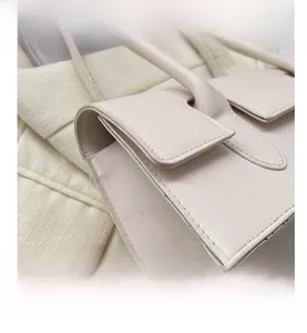 Detail showing high-quality stitching and handle of cream white designer shoulder bag