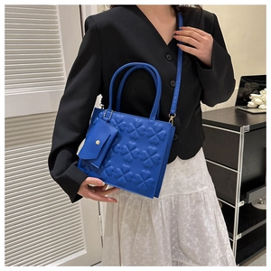 Detail of blue square tote with 3D clover embossing and a matching mini envelope bag