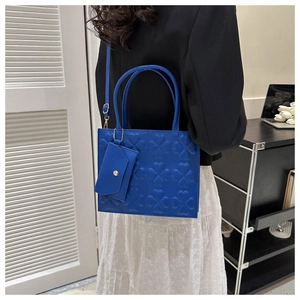 Detail of royal blue handbag featuring clover embossed texture and mini chain envelope pouch