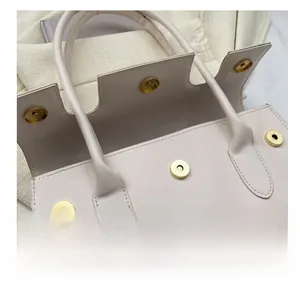 Detail view of the secure magnetic clasp closure on this beige faux leather handbag