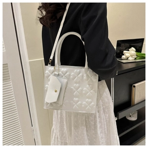 Detailed texture of white embossed clover tote bag with small matching pouch and strap