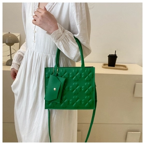 Detail of emerald green tote bag featuring embossed clover patterns and a small coin purse