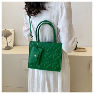 Detailed view of a green clover embossed square handbag with a mini coin purse attachment