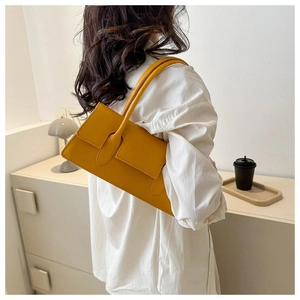 Model wearing bright yellow minimalist shoulder bag against a soft home background